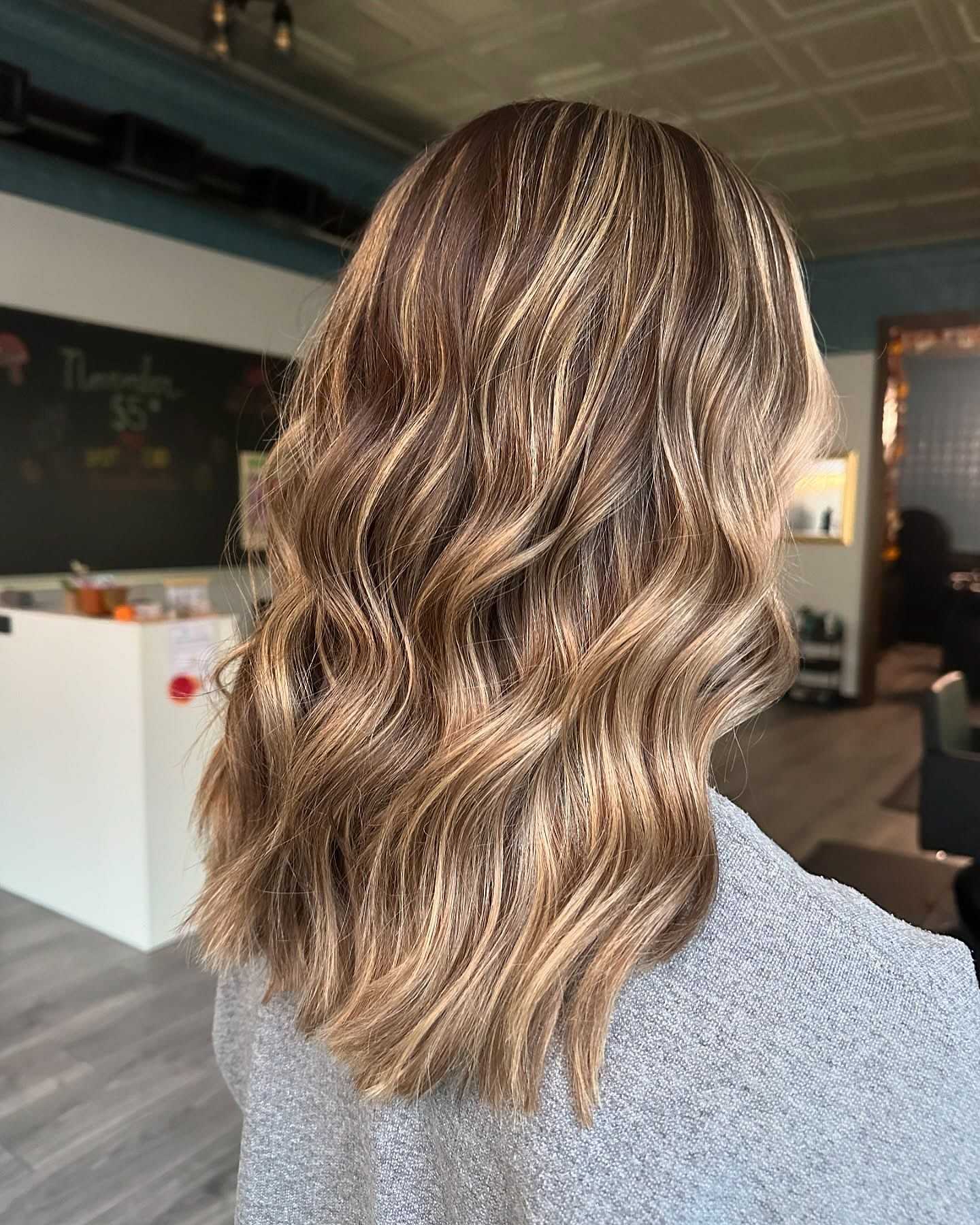 Wavy blonde hair with highlights in a salon setting.