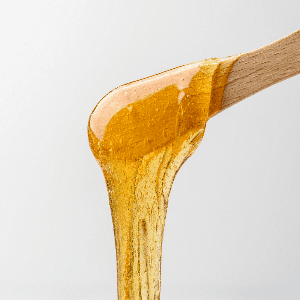 Honey drizzling from a spoon against a white background.